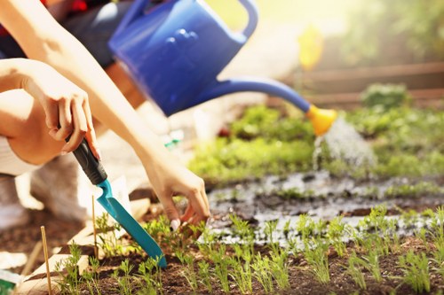 Gardener holding tools and wearing protective gloves at a residential garden